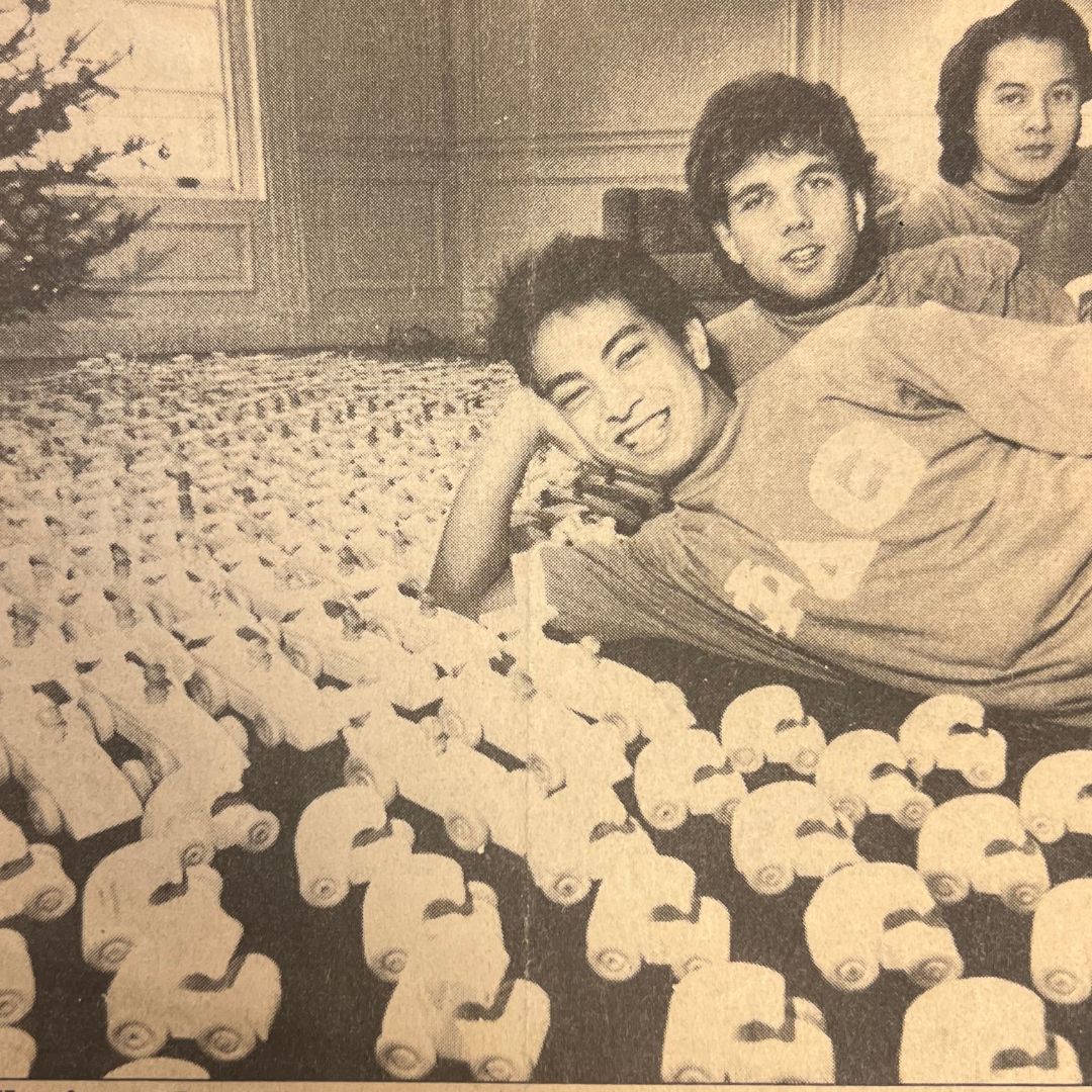 Newspaper clipping of fraternity brothers posed with wooden toy cars
