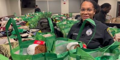 A Cambridge police officer stands amidst the prepared donated gift bags for seniors.