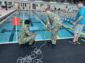 Two Sea Cadets place their robot into a pool