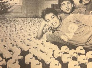 Newspaper clipping of fraternity brothers posed with wooden toy cars